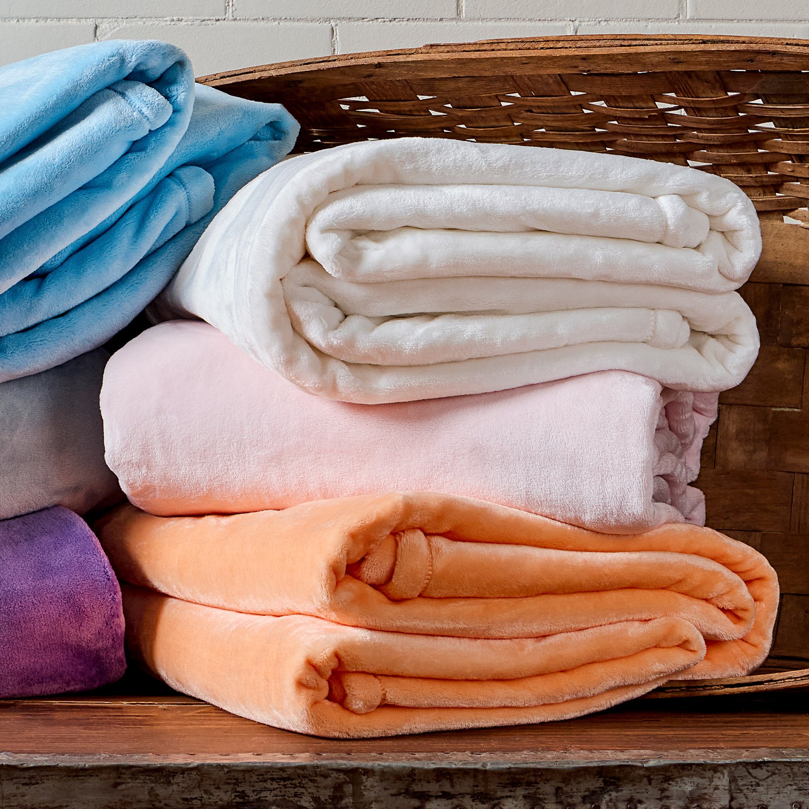 AMERICAN BLANKET COMPANY - LUSTER LOFT BLANKETS - COLORFUL STACKS OF LUSTER LOFT BLANKETS FALLING OUT OF A BASKET