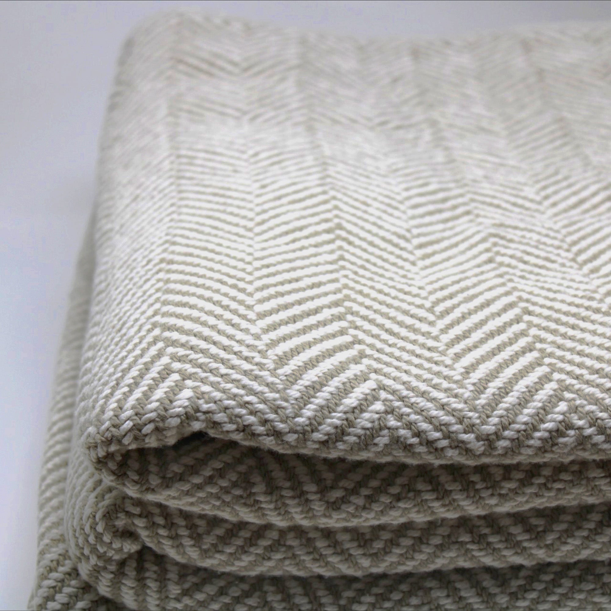 American Blanket Company - 100% Cotton Bed Blanket, Feather Weave Pattern Blanket - Close up of the woven herringbone cotton blanket in khaki and white, showing the tight knit construction of the pattern.
