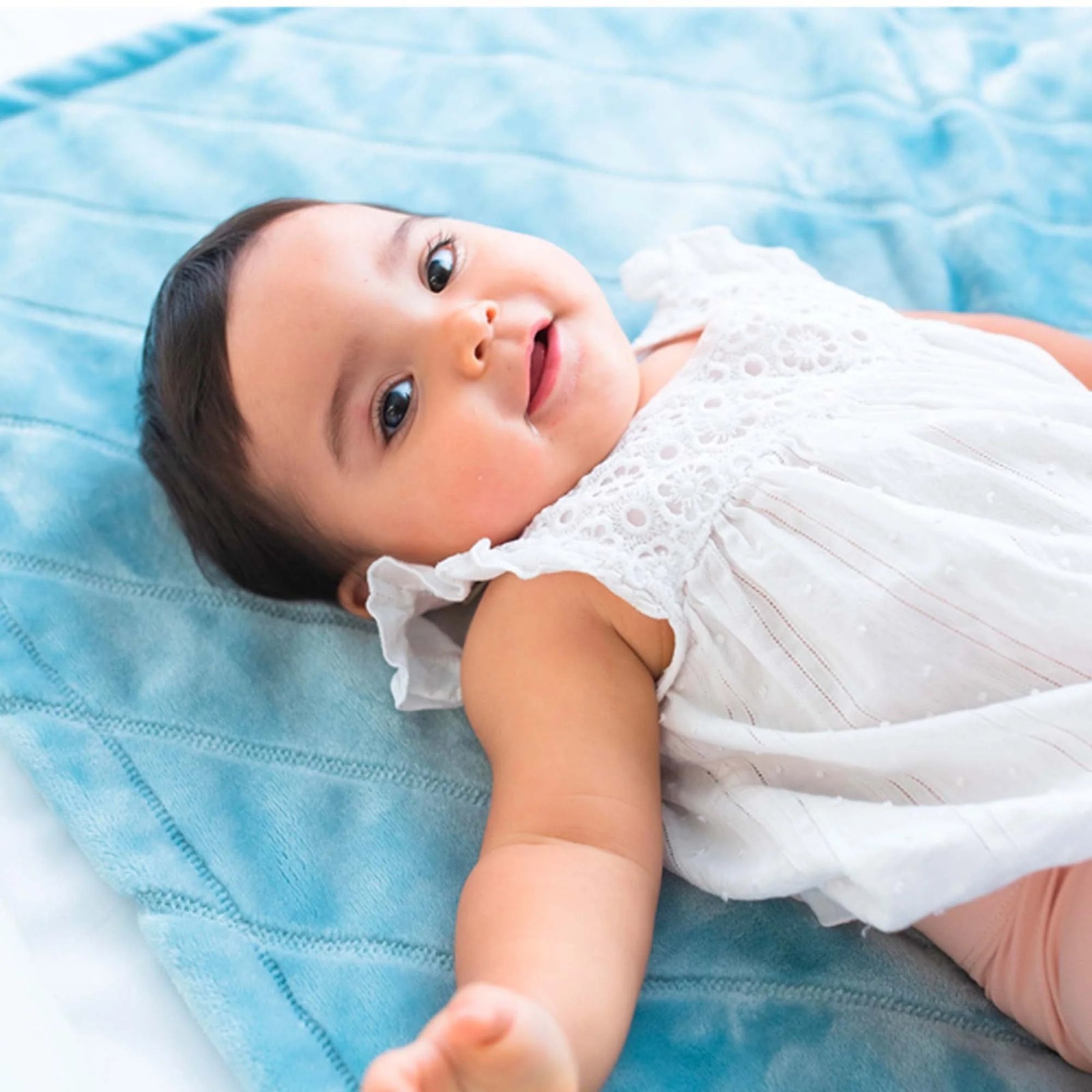 AMERICAN BLANKET COMPANY - FLEECE BABY BLANKETS - A BABY LYING ON A FLEECE LUSTER LOFT QUILT SMILING UP AT THE CAMERA
