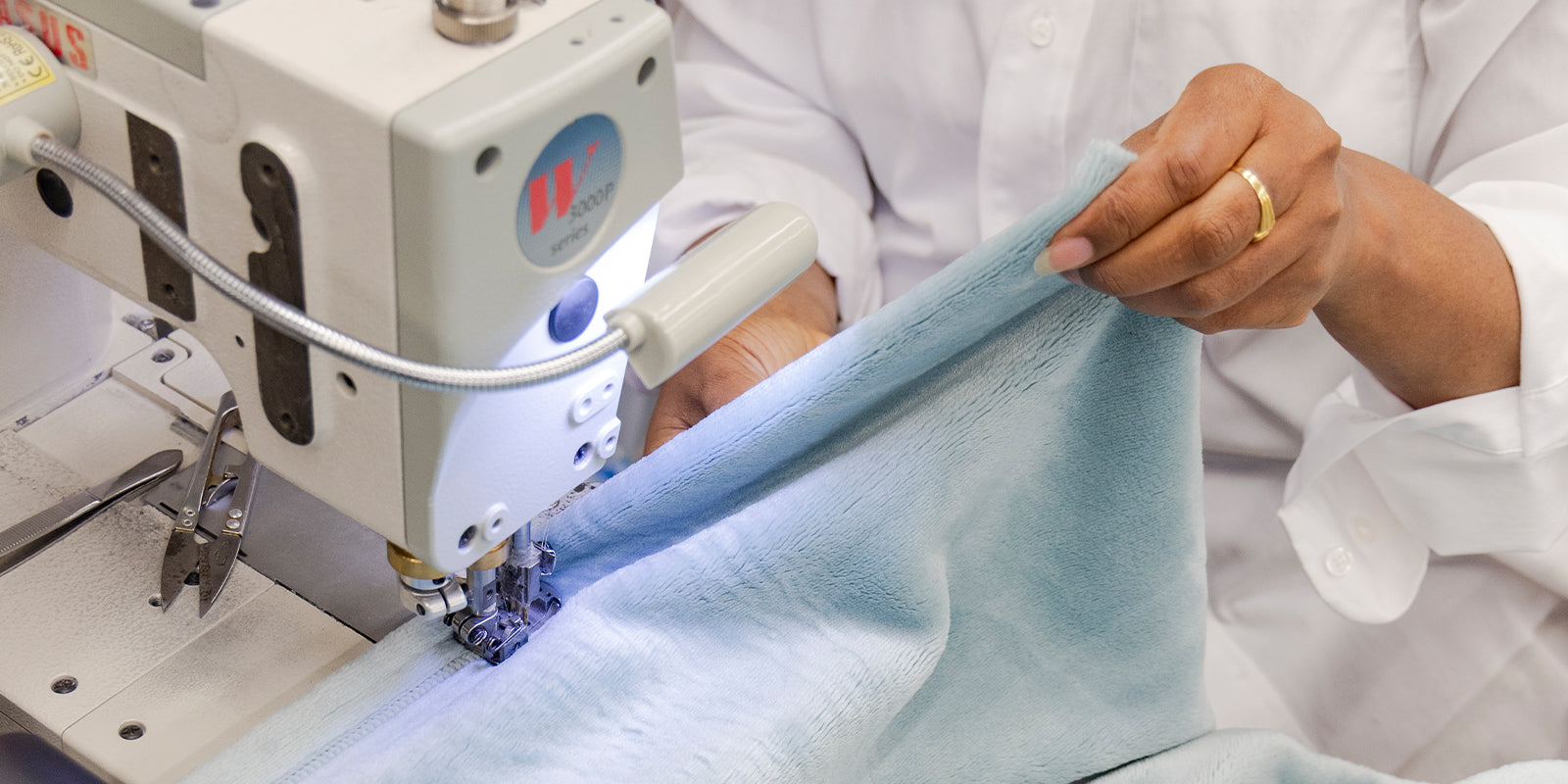 American blanket company - Luster Loft Fleece Blank - Person using a sewing machine sewing a luster loft fleece blanket