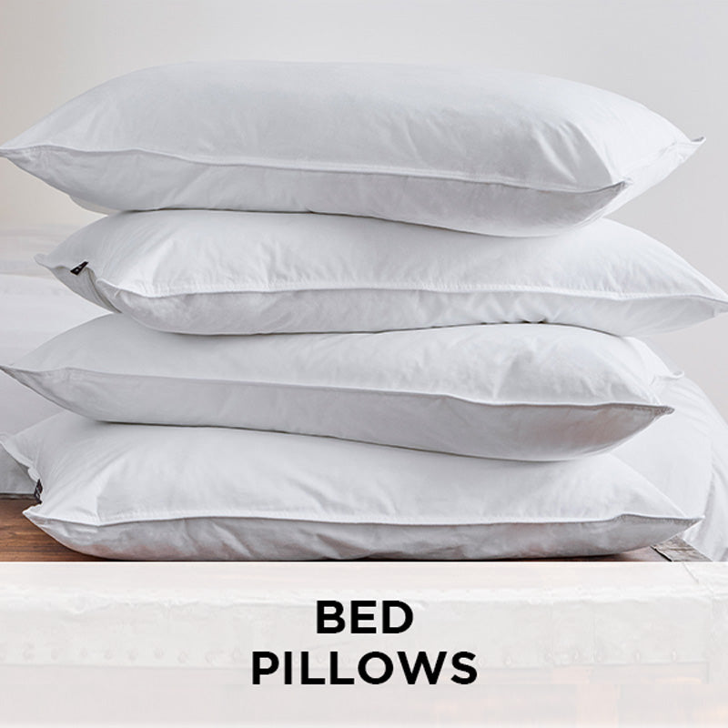 AMERICAN BLANKET COMPANY - BED PILLOWS - CRISP WHITE HYPOALLERGENIC BED PILLOWS STACKED ON TOP OF EACH OTHER ON A WOODEN TRUNK 