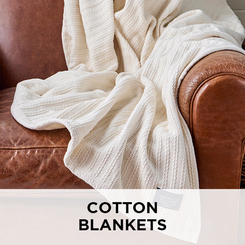 AMERICAN BLANKET COMPANY - CABLE WEAVE COTTON BLANKET - COTTON BLANKET DRAPED OVER A LIGHT LEATHER VINTAGE ARMCHAIR