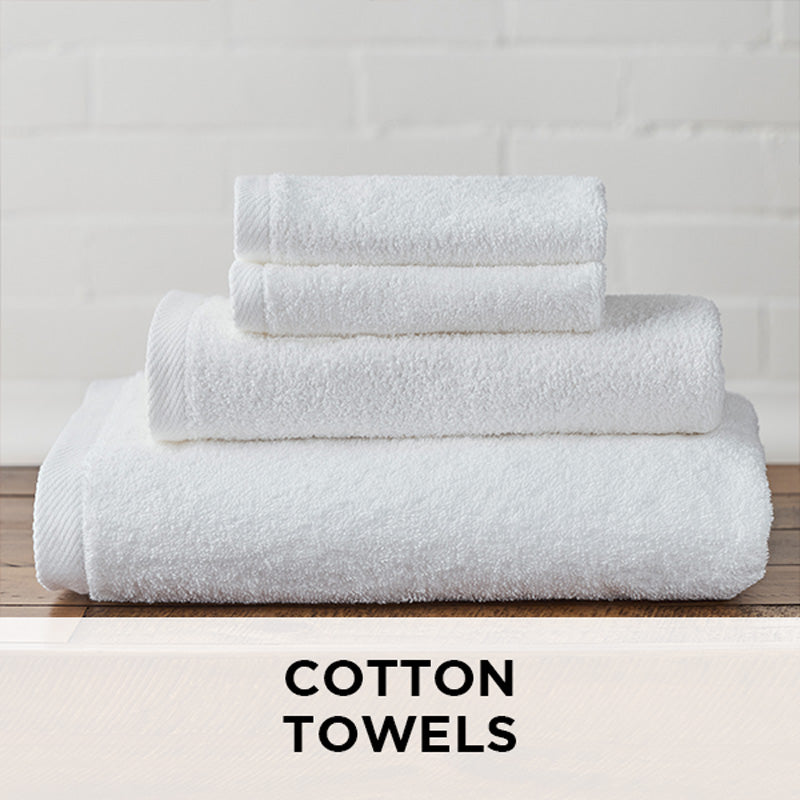 AMERICAN BLANKET COMPANY - COTTON TOWELS - NEATLY FOLDED CRISP WHITE COTTON TOWELS ON A WOODEN TRUNK.