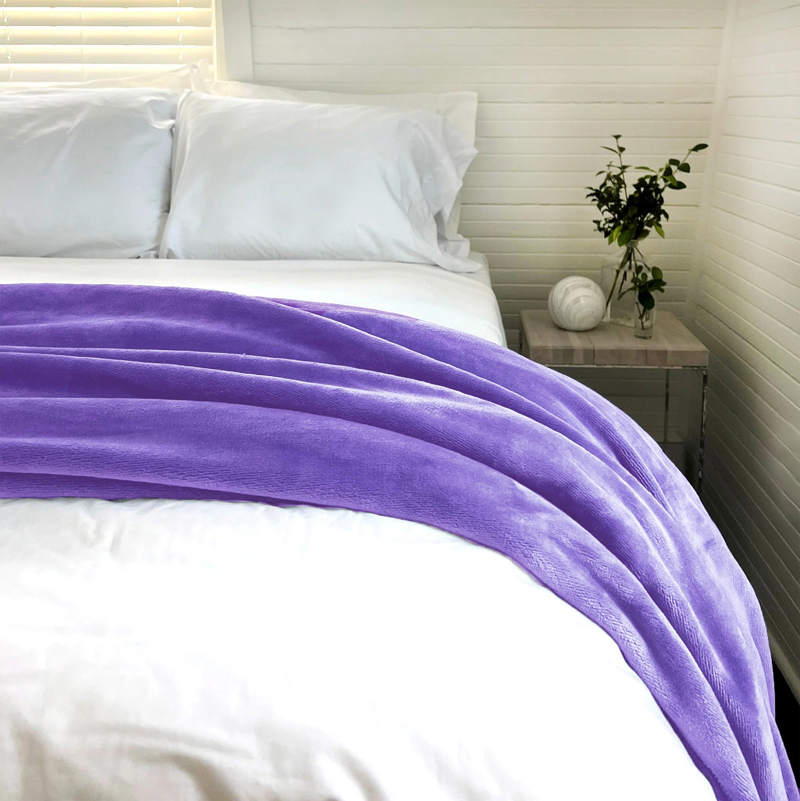 American Blanket Company - Light Weight Luster Loft Fleece Blankets - Purple light weight luster loft blanket on top of comforter covered bed in a white room with fluffed bed pillows.