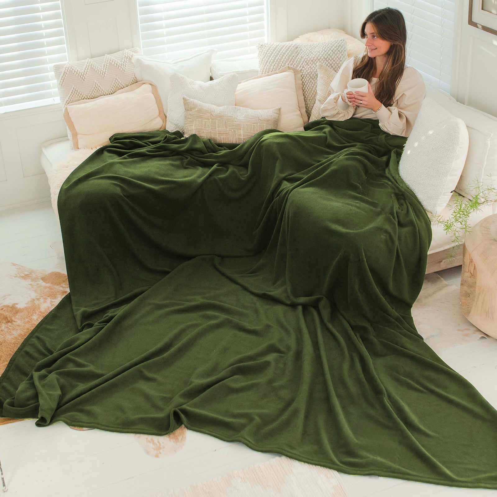American Blanket Company - Peaceful Touch Fleece Blankets - Custom Fleece Blankets - Pictured is a young woman under an olive peaceful touch custom blanket that exceeds past the couch and over the floor.