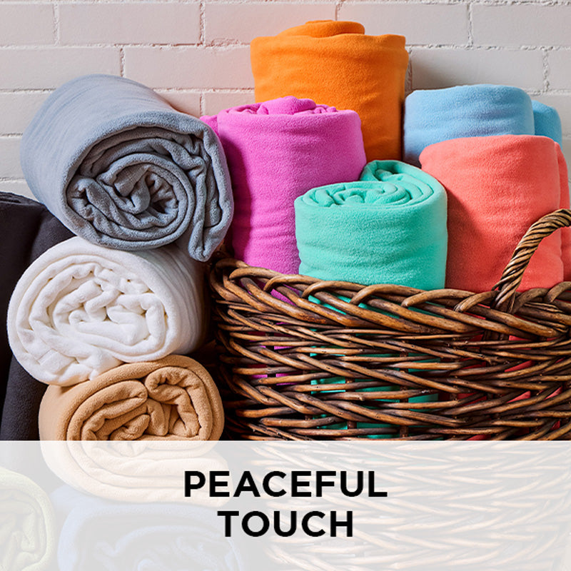 AMERICAN BLANKET COMPANY - PEACEFUL TOUCH BLANKETS - COLORFUL ROLLS OF PEACEFUL TOUCH BLANKETS FALLING OUT OF A BASKET