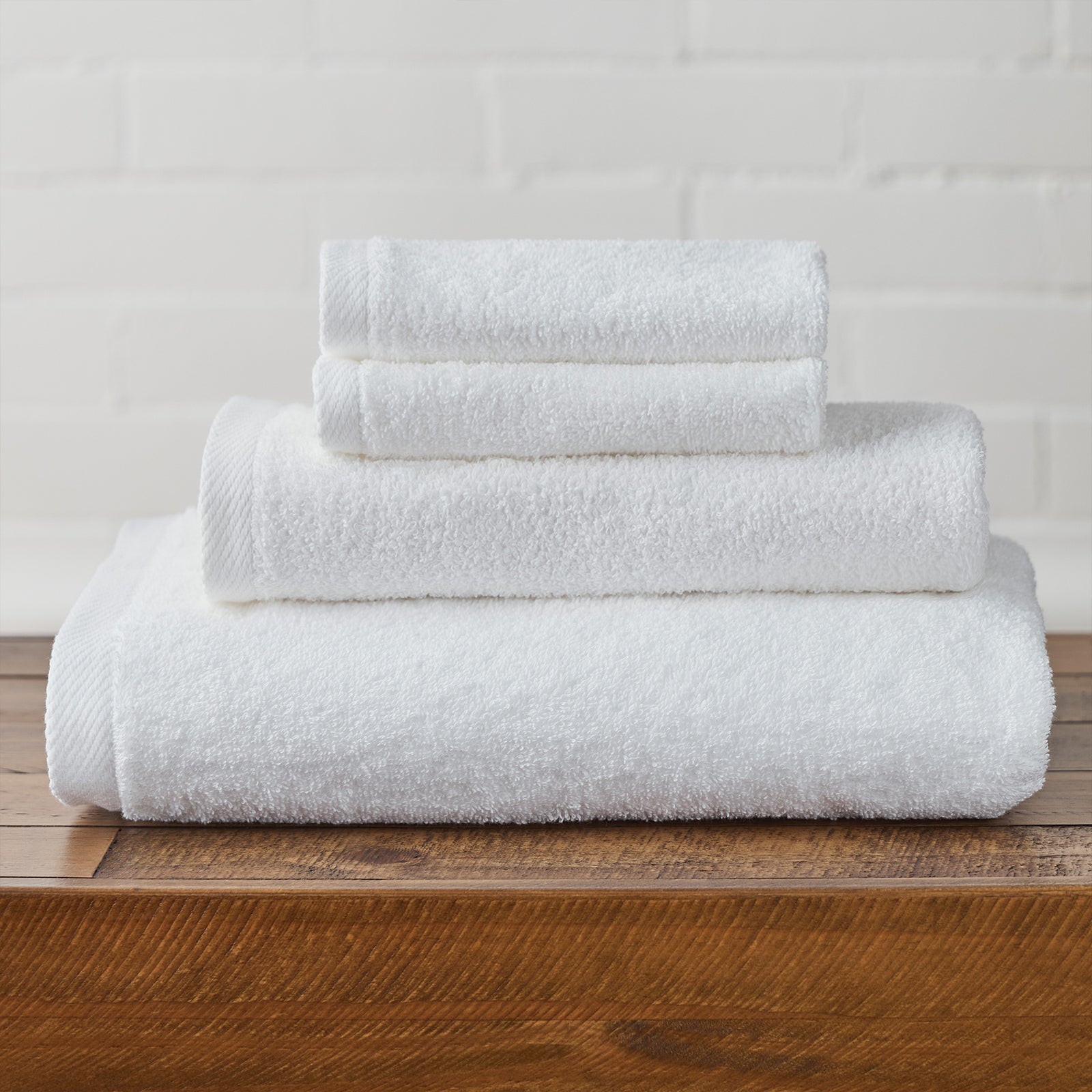 AMERICAN BLANKET COMPANY - COTTON TOWELS - NEATLY FOLDED CRISP WHITE COTTON TOWELS ON A WOODEN TRUNK.