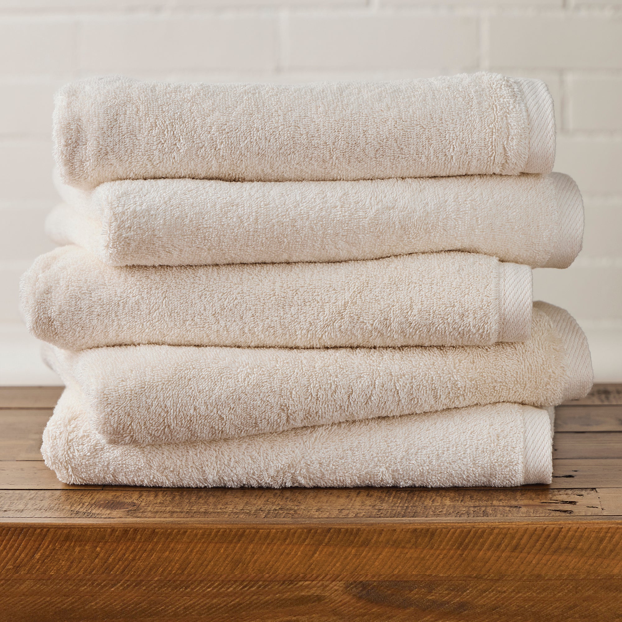 AMERICAN BLANKET COMPANY - COTTON TOWELS - NEATLY FOLDED CRISP BEIGE COTTON TOWELS ON A WOODEN TRUNK.