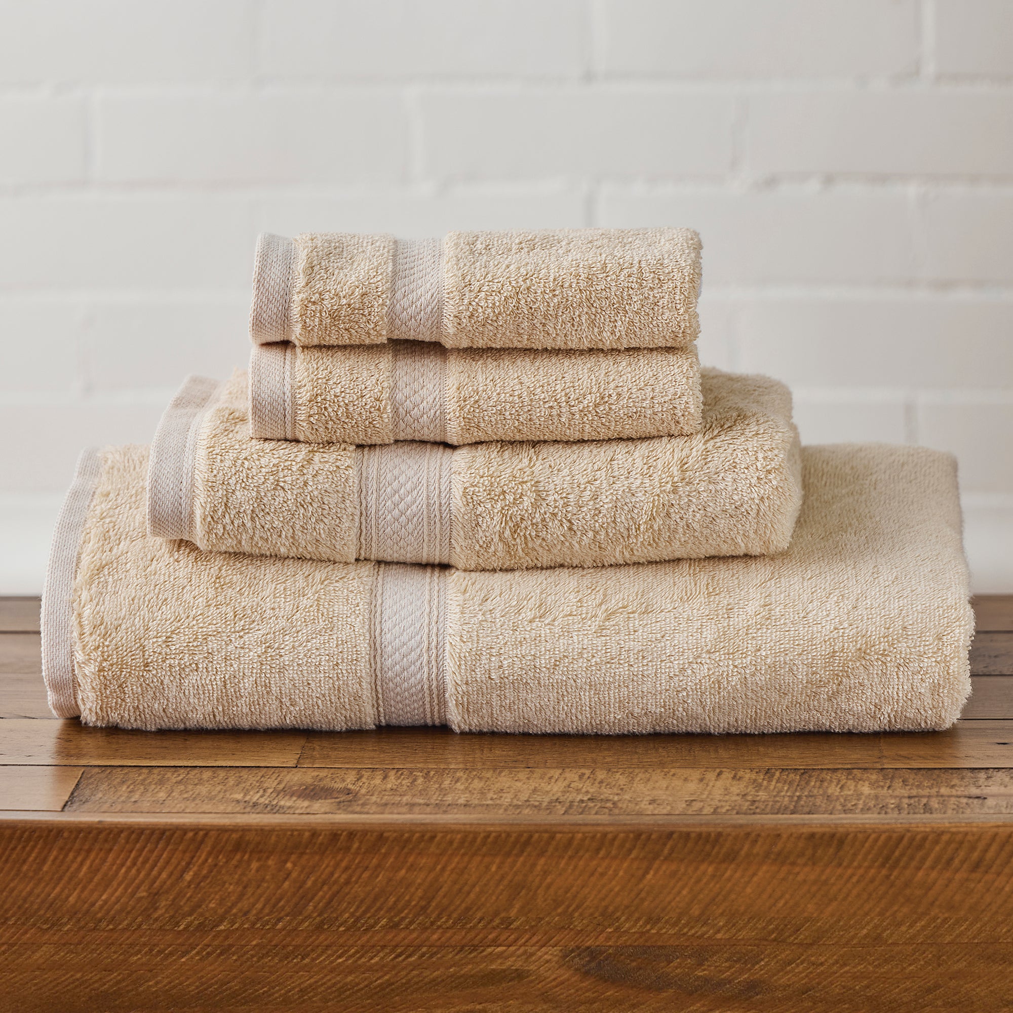 AMERICAN BLANKET COMPANY - COTTON TOWELS - NEATLY FOLDED GOLDEN COTTON TOWELS ON A WOODEN TRUNK.