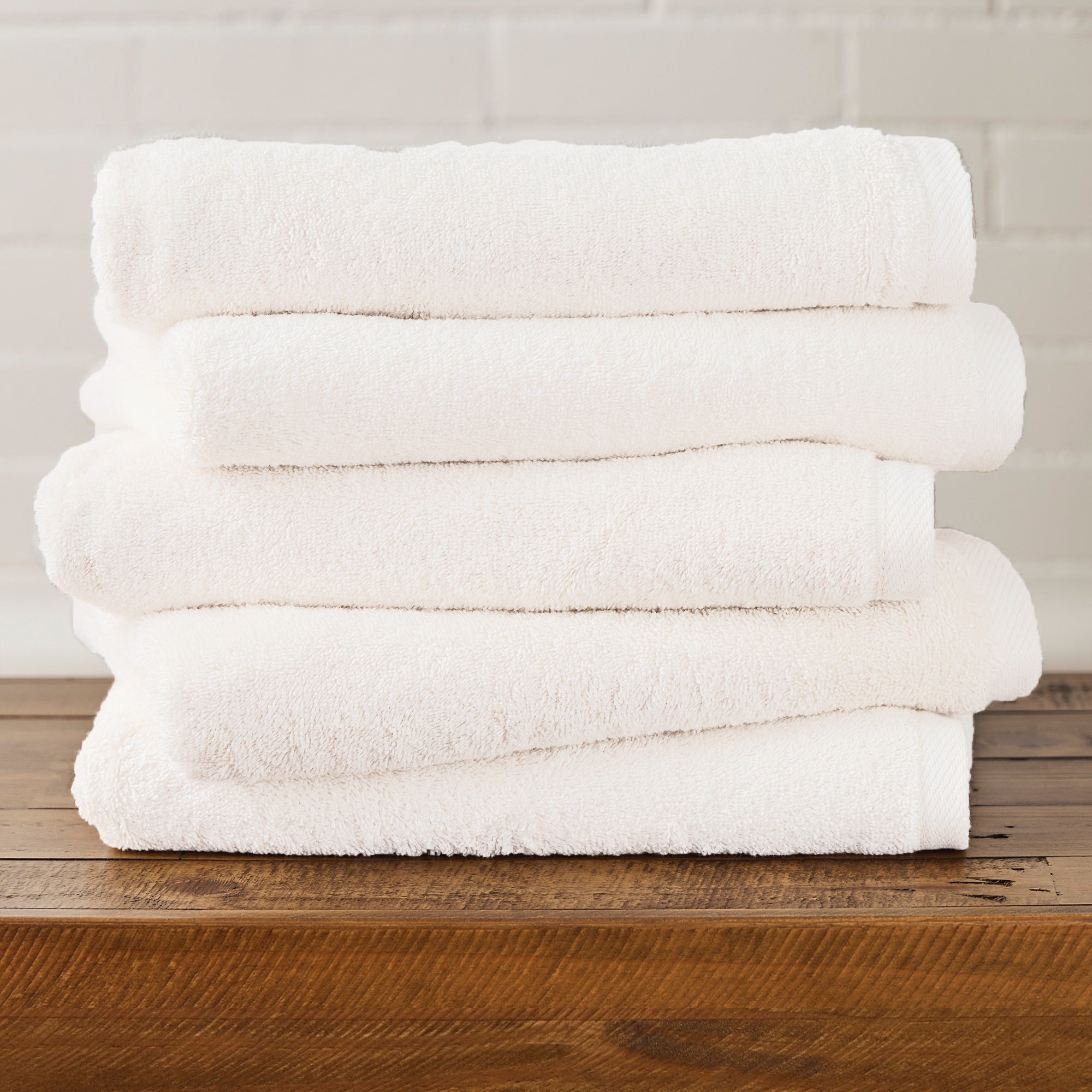 Stack of white towels on a wooden surface with a neutral background
