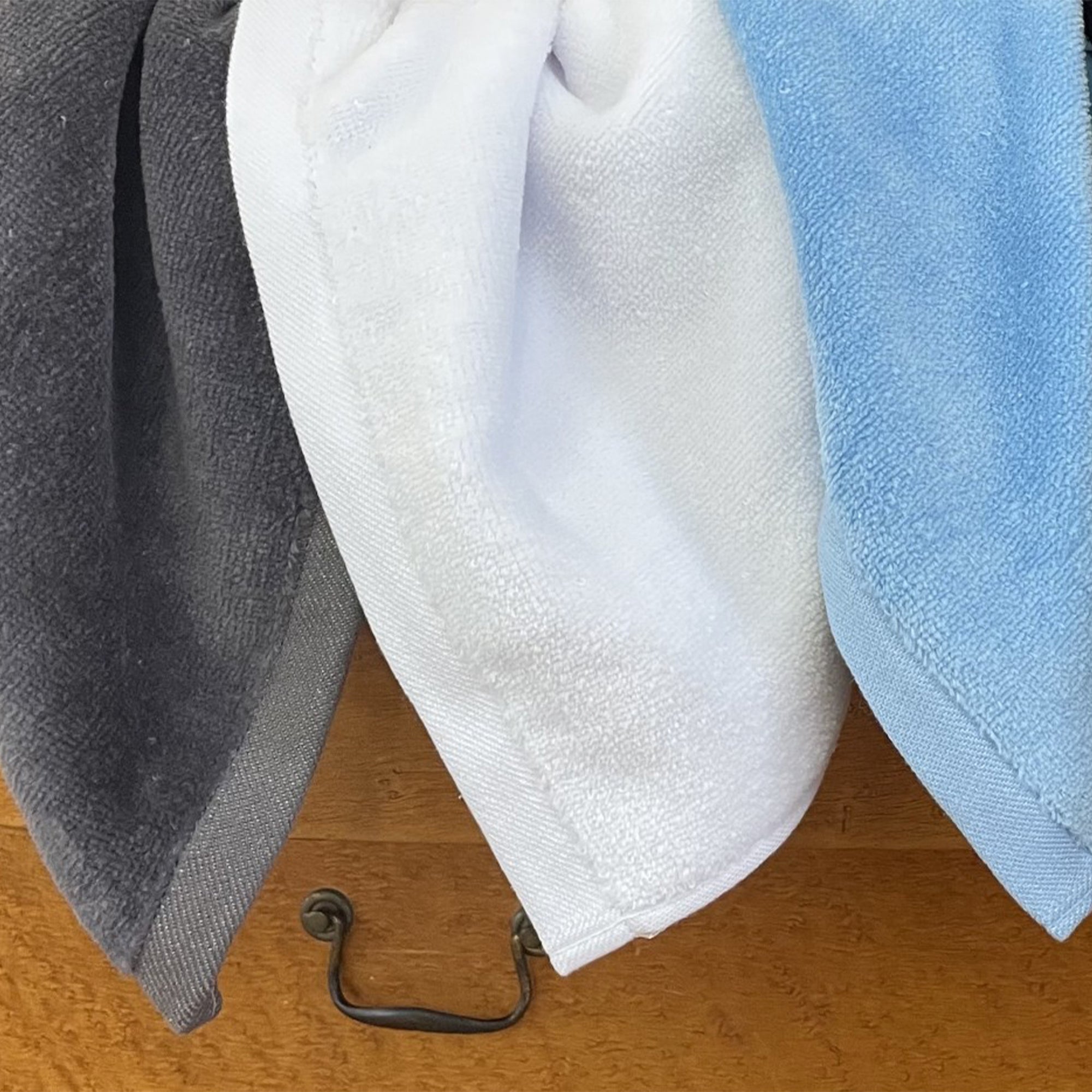Made in the USA towels - American Blanket Company - Three towels in gray, white, and blue hanging on a wooden surface with a metal hook.