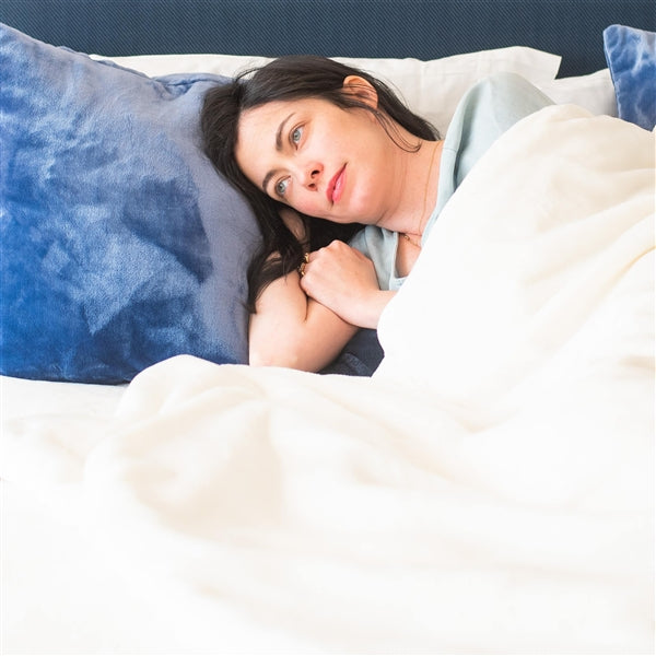 American Blanket Company - Luster loft weighted blanket - Pictured young woman relaxing under a luster loft weighted blanket.