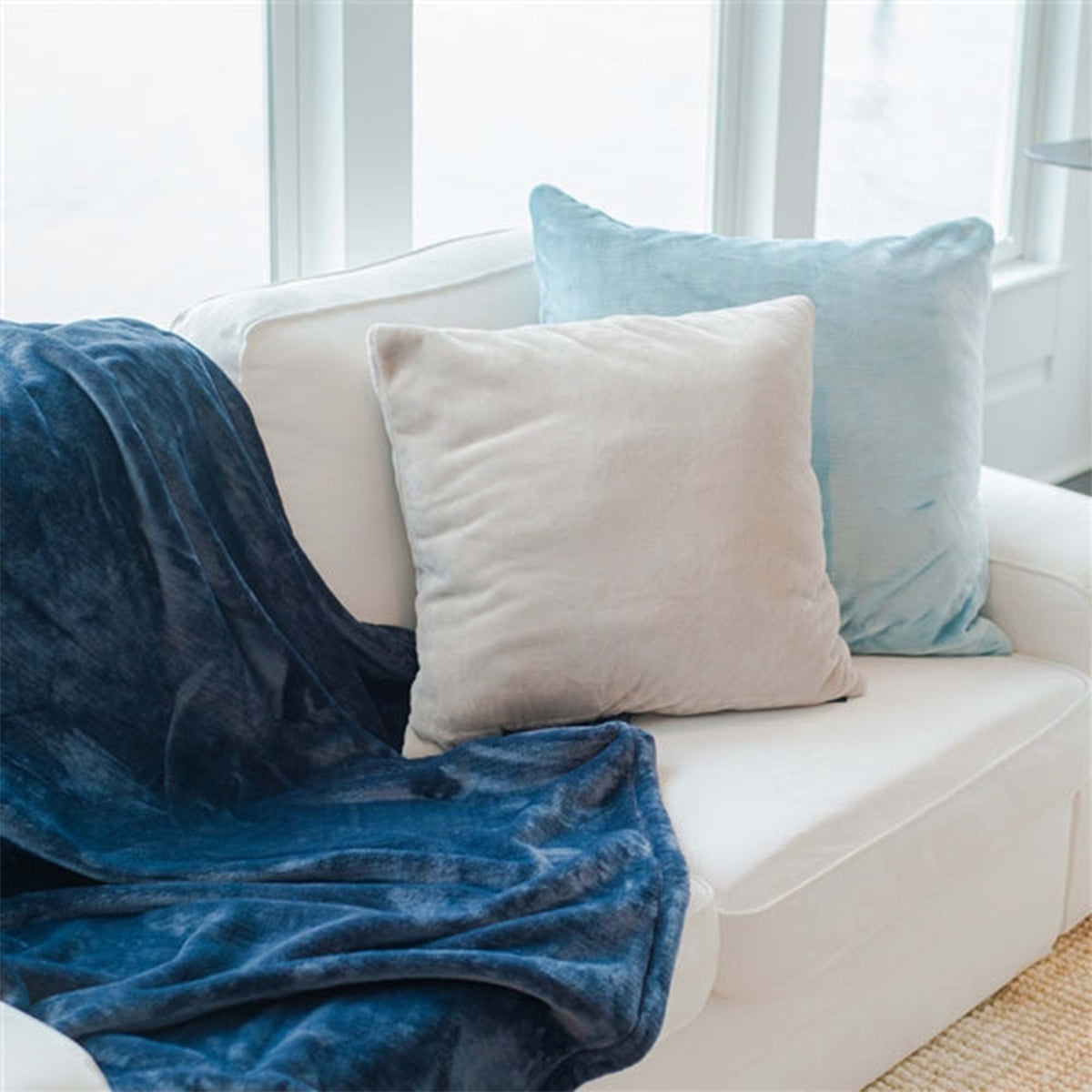 White and blue throw pillows on white couch - Luster Loft - luster loft fleece throw pillows - American Blanket Company